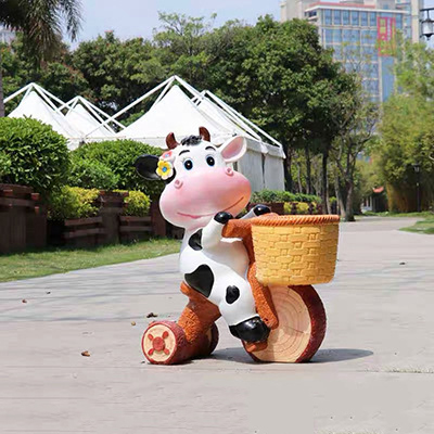 牛雕塑-動物園一只騎車的玻璃鋼牛雕塑高清圖片